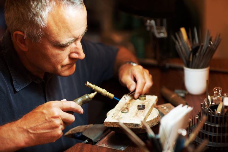 Jeweller using a blowtorch while he works on a ring